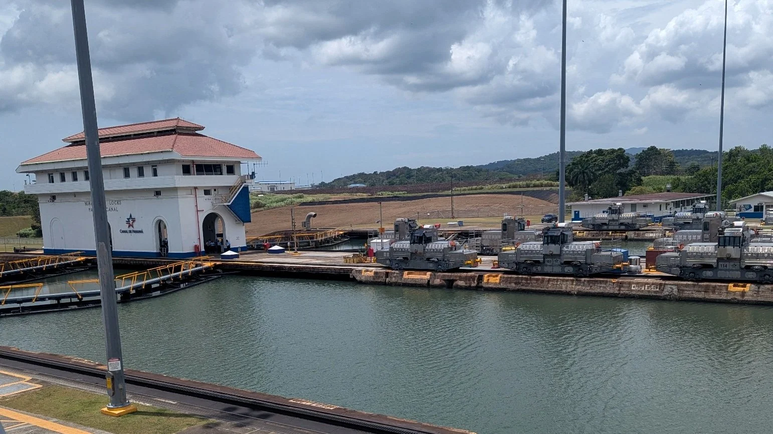 Electric towing locomotives and lock infrastructure at the Panama Canal's Miraflores Locks, seen from the visitor observation area.