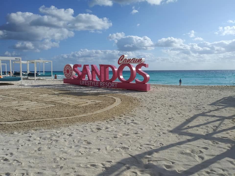 sandos cancun sign on a manicured beach