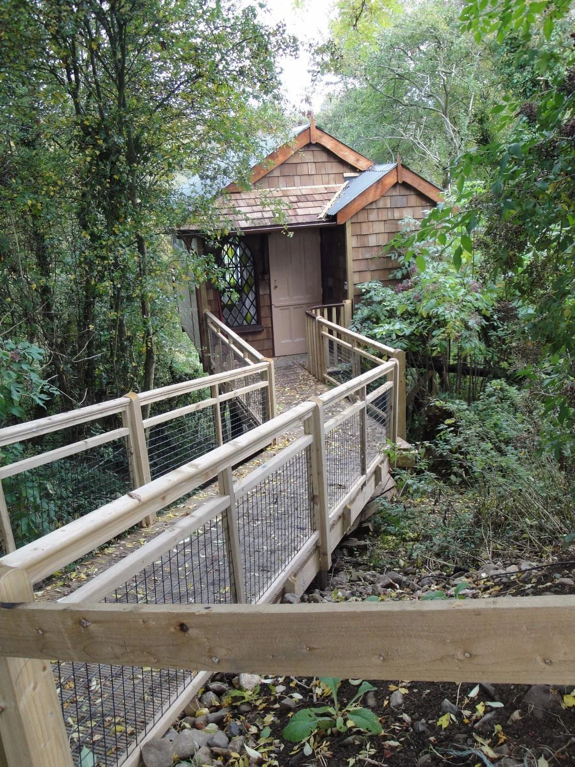 Wooden walkway leading through the trees to the secluded treehouse at Lawcus Farm in County Kilkenny, Ireland.