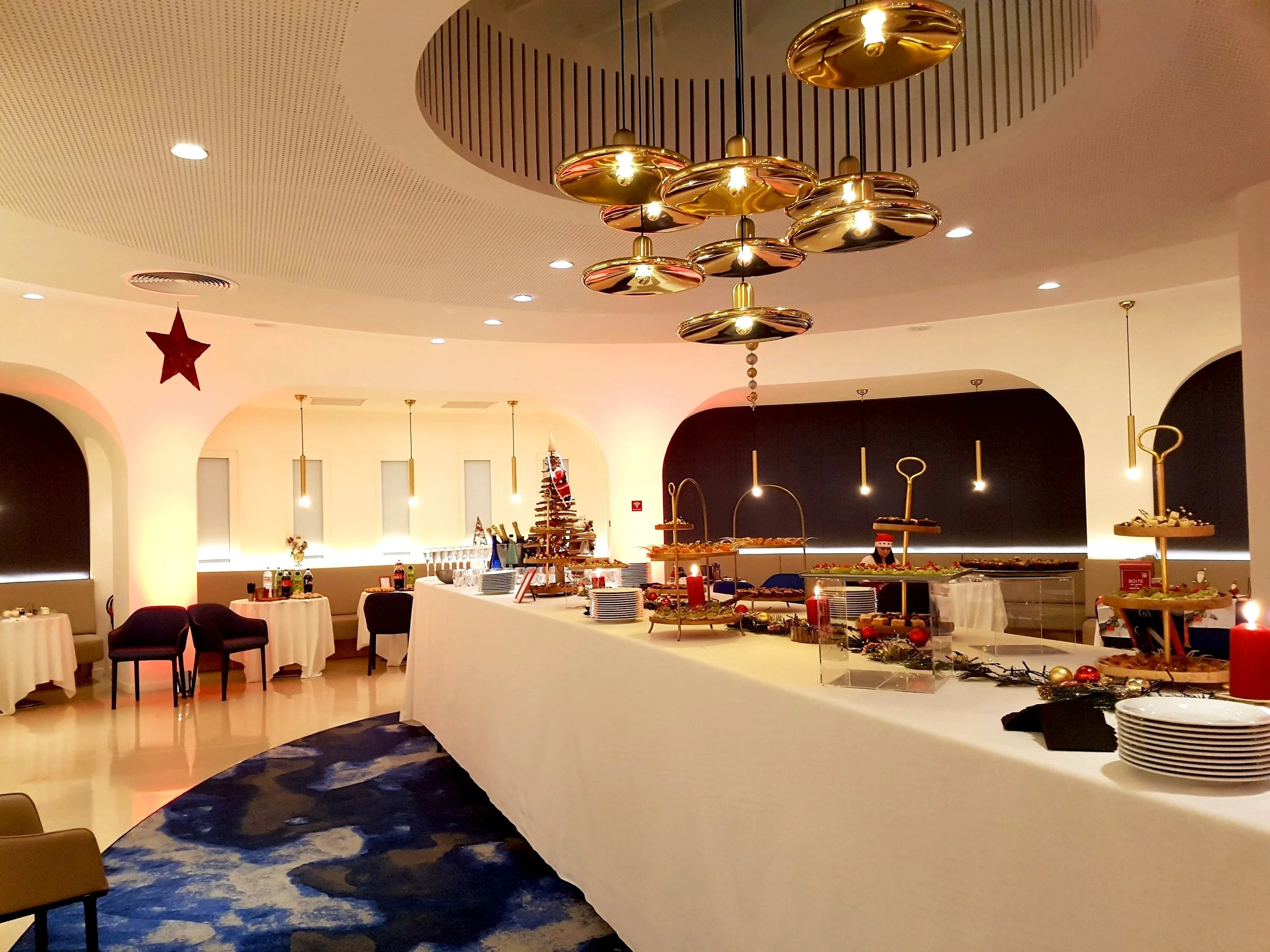 Salle de réception décorée pour Noël avec buffet, sapin, guirlandes et décorations festives.