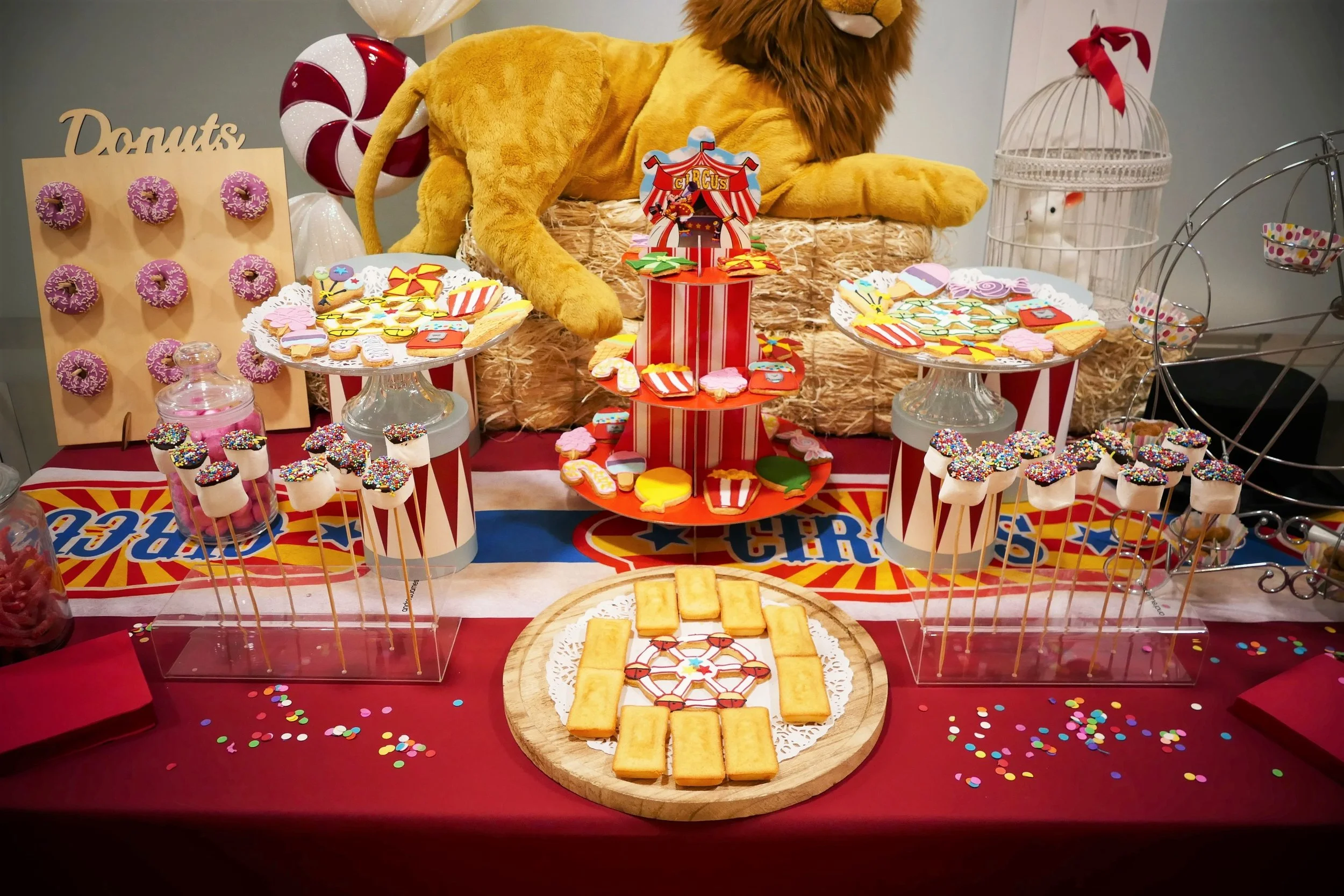Décoration de fête de cirque avec gâteau, bonbons et friandises, lion en peluche et cage à oiseaux, réservée à un spectacle de cirque.