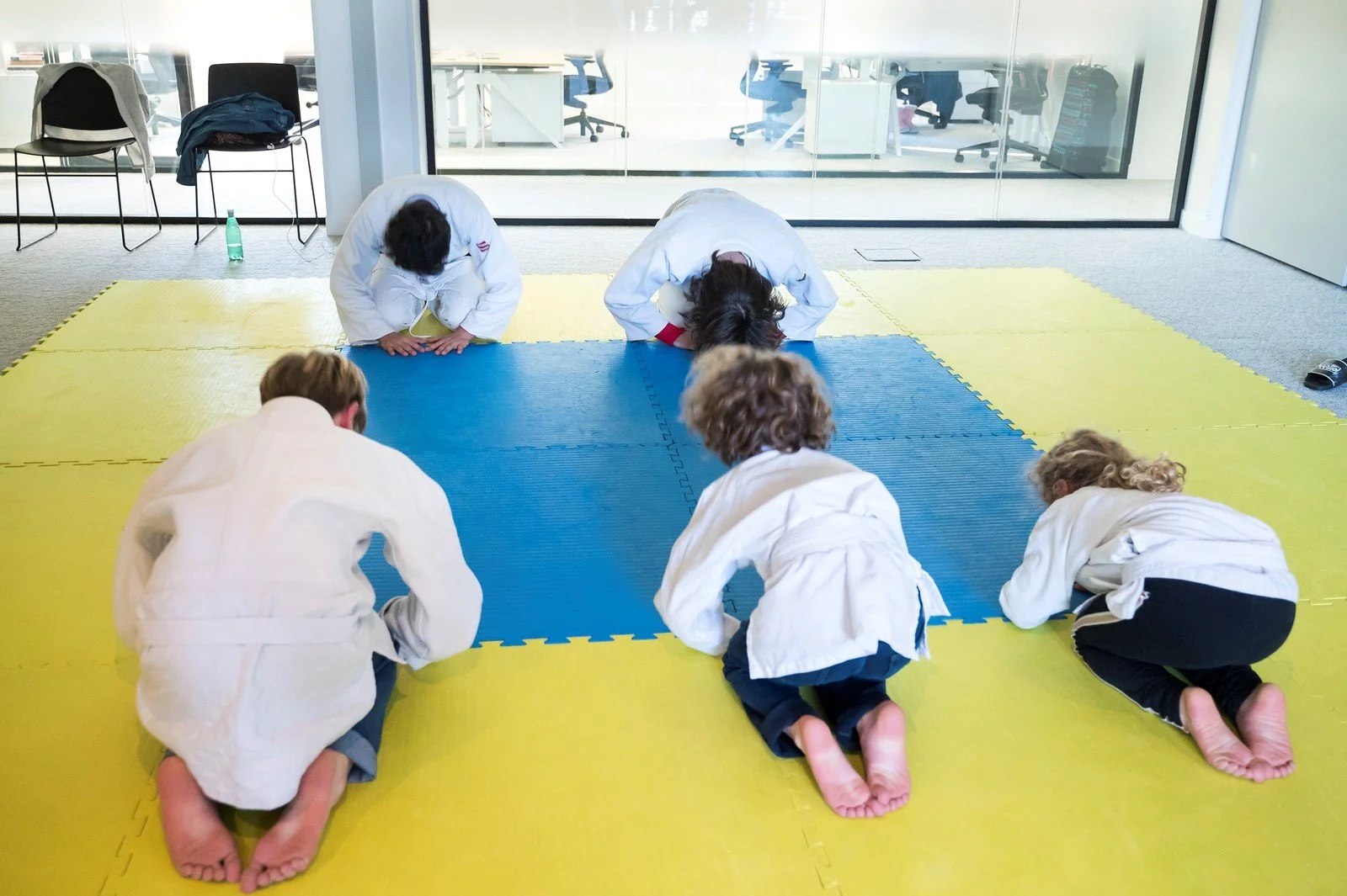 Groupe d'enfants en kimono pratiquant le judo sur un tapis de sol en salle d'arts martiaux.family day 