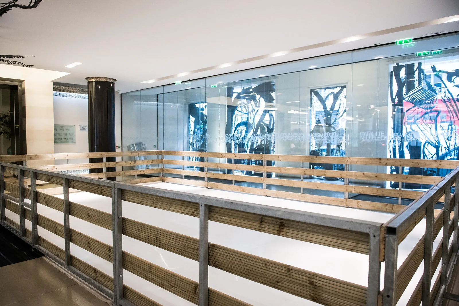Espace en construction avec une structure en bois et un mur en verre avec des œuvres d'art modernes