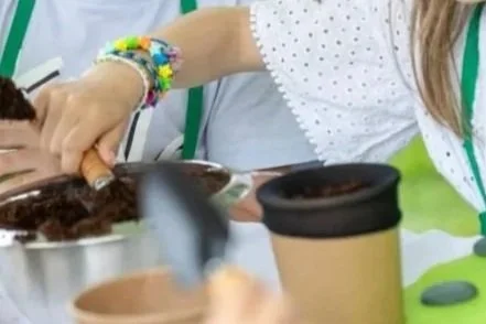 Une personne en train de préparer ou servir un repas, avec une tasse à café en carton sur la table.