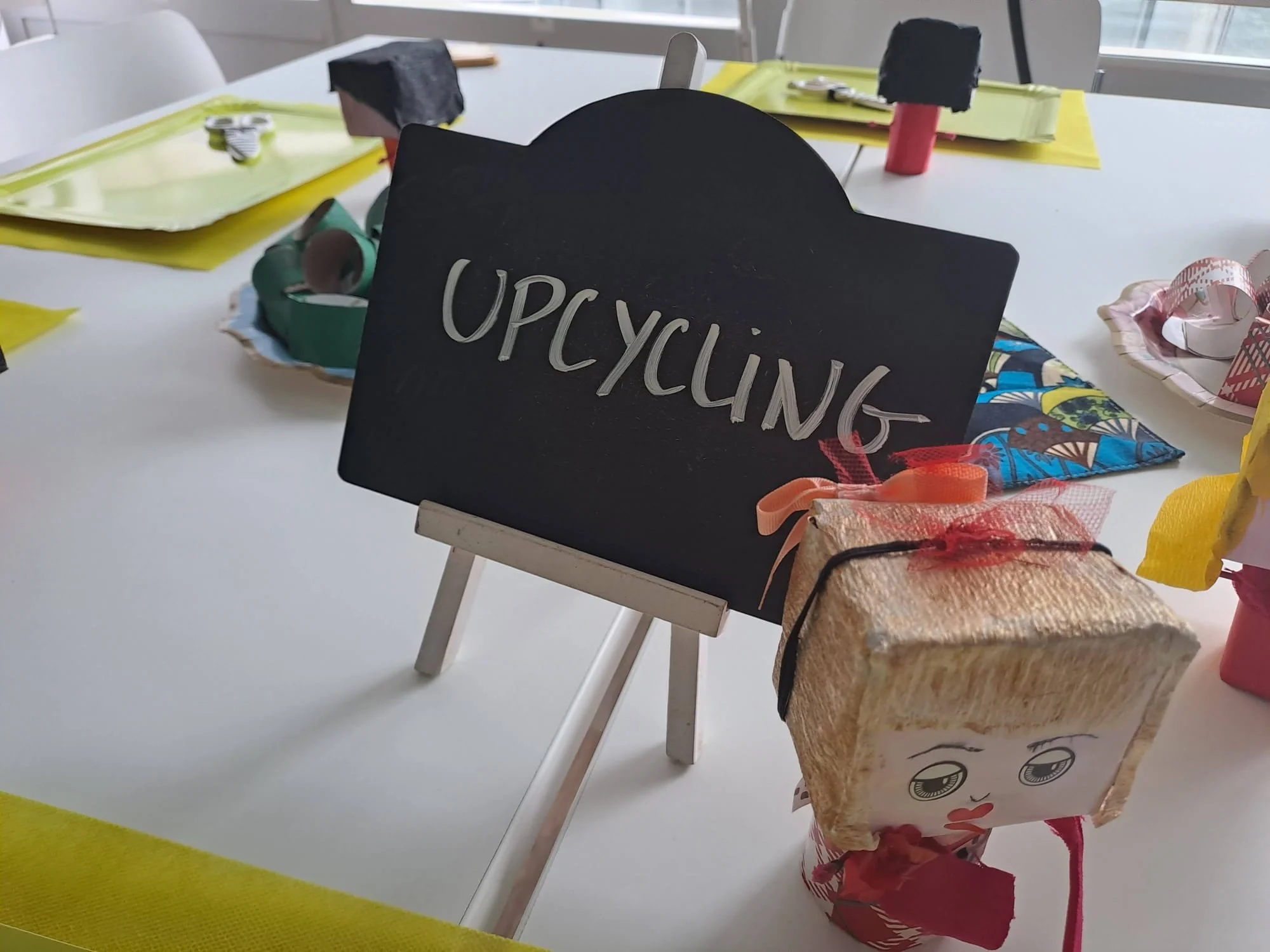 Une table avec des objets artisanaux et un panneau en ardoise écrit "OPCYCLING".