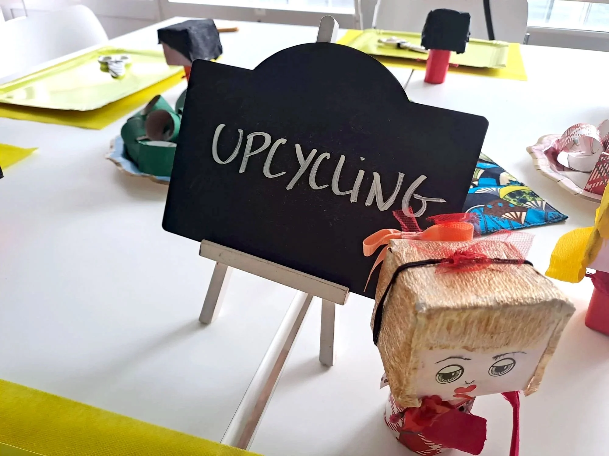 Une table avec des objets artisanaux et un panneau en ardoise écrit "OPCYCLING".