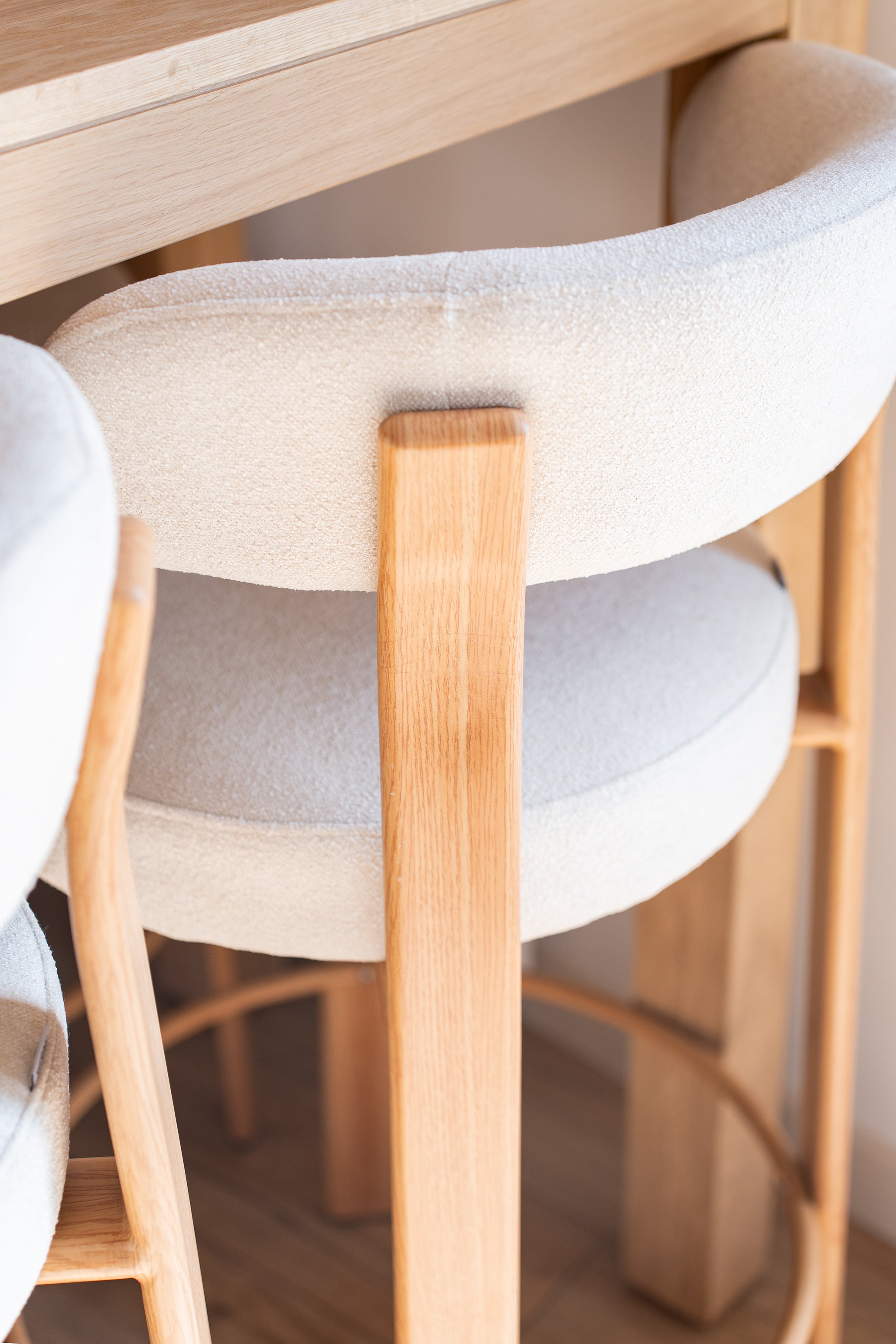 Chaise en bois avec assise rembourrée de tissu beige, vue rapprochée.