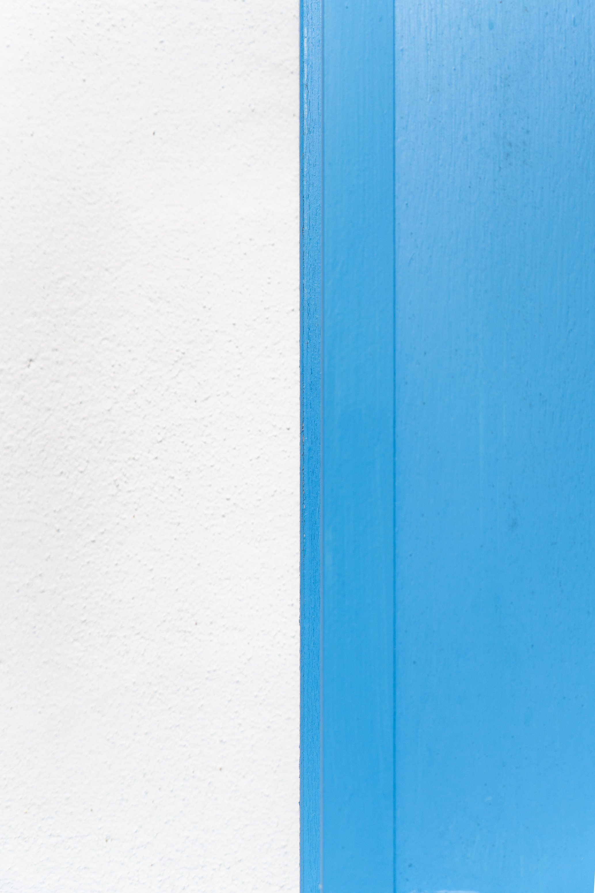 Une porte bleue située à côté d'un mur blanc