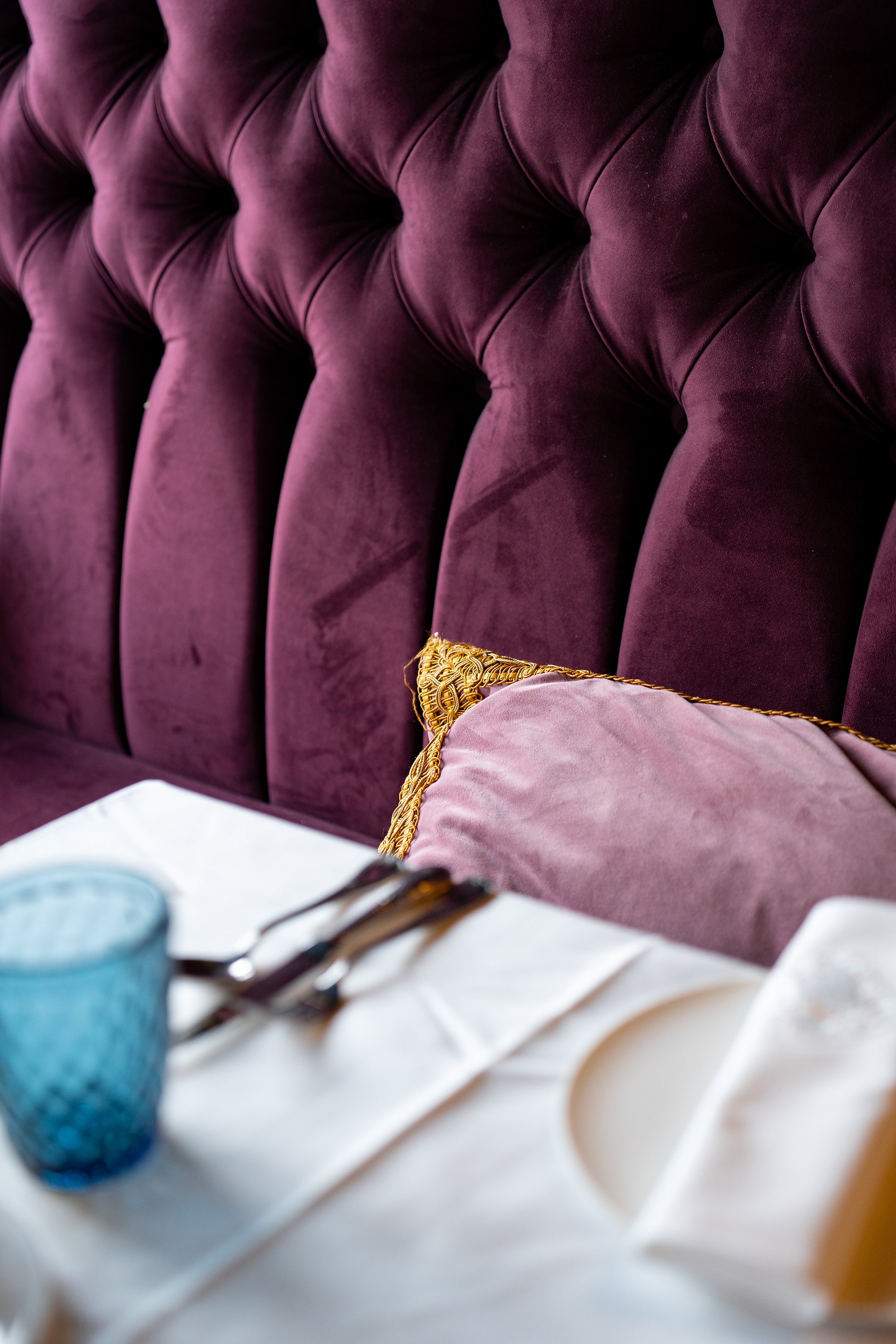 Garnet-tissu de velours violet foncé avec coussin assorti et détails dorés, partie d'un mobilier élégant, probablement une tête de lit ou un canapé.