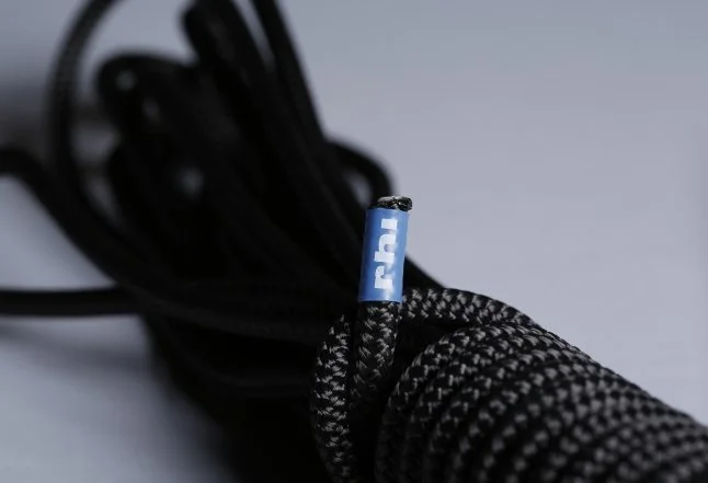 Black and white braided headphone cable with a blue connector on a gray background.