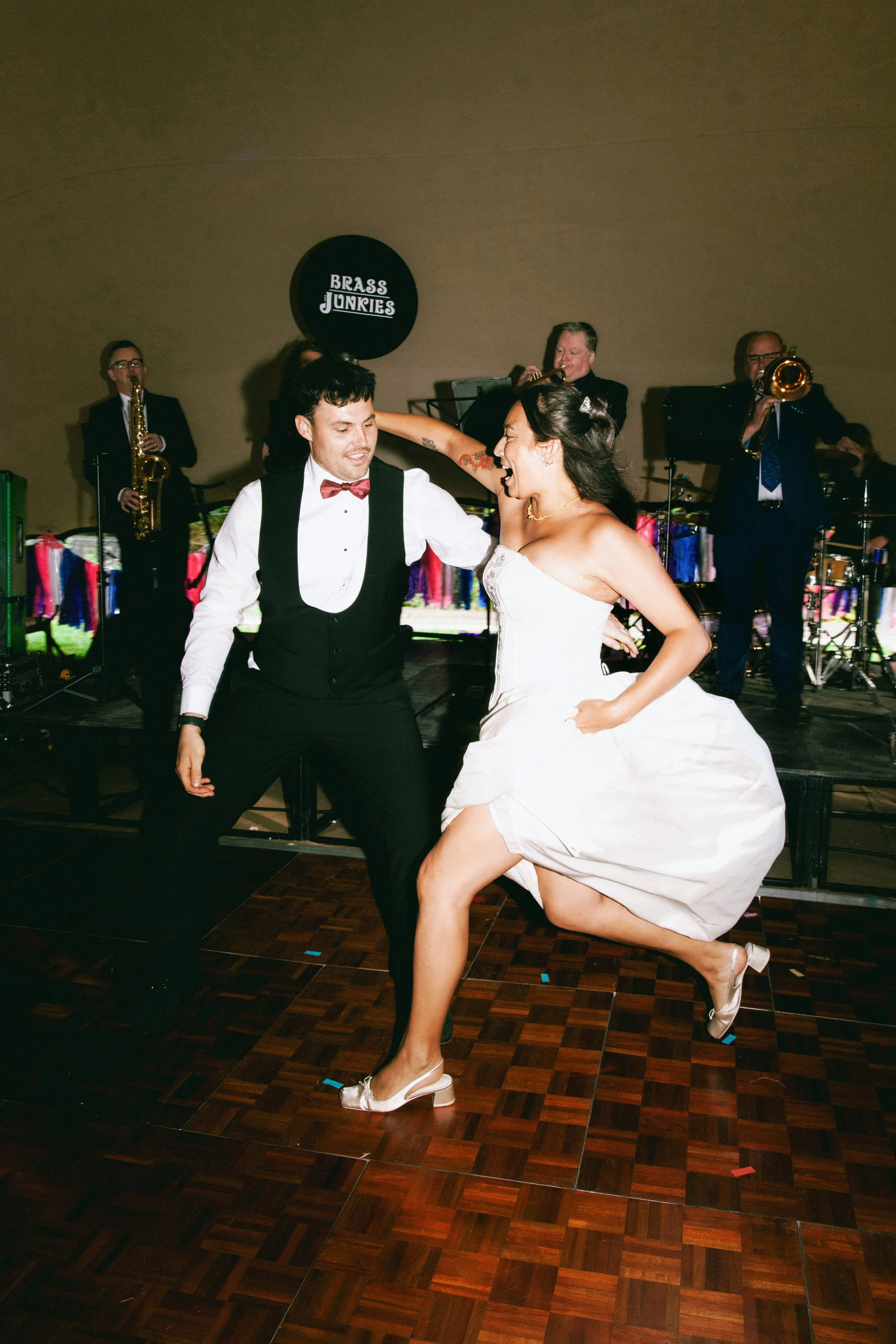A bride and groom dancing together at their wedding reception with a band playing in the background.