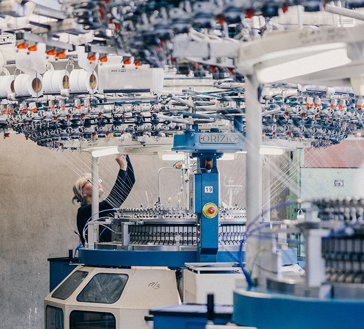 A woman working with industrial textile machinery in a factory.