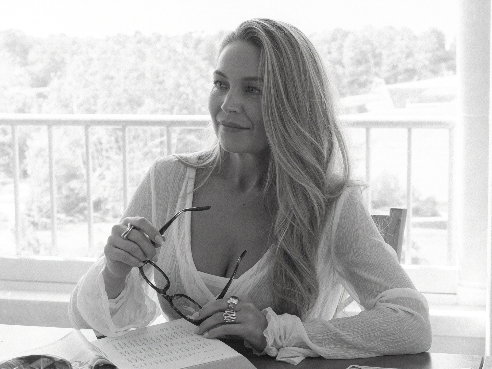 Brielle Fontaine reclining playfully in a white chair during a bright editorial studio photoshoot.