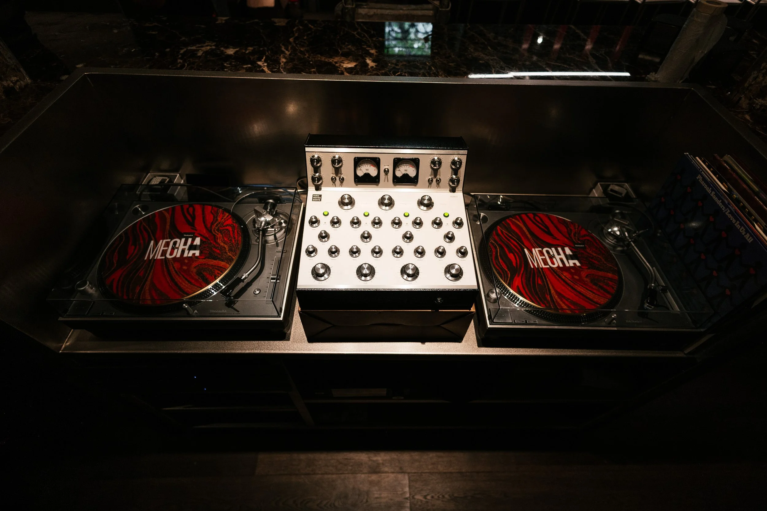 Equipo de DJ con giradiscos y mezcladora en un espacio con iluminación tenue.