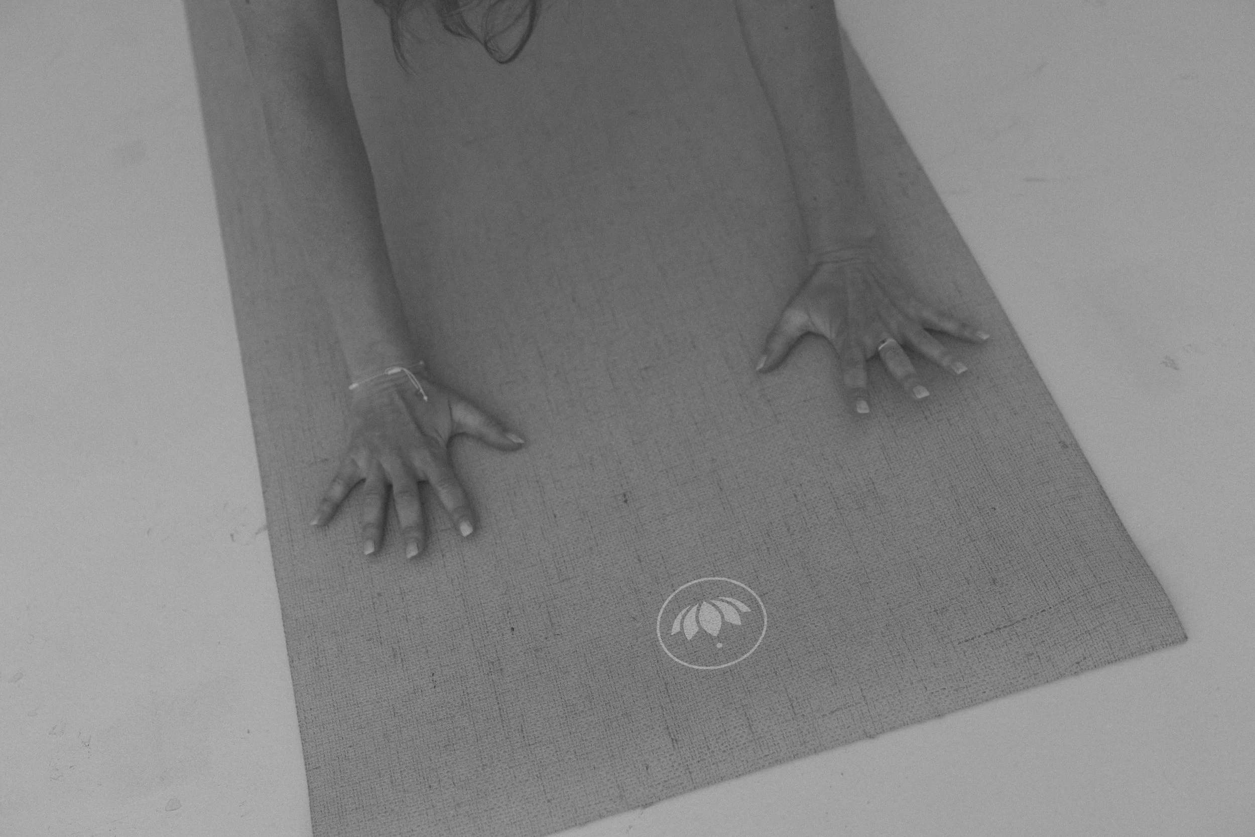 Hände in einer Yoga-Haltung auf einer Element-Yoga-Matte.