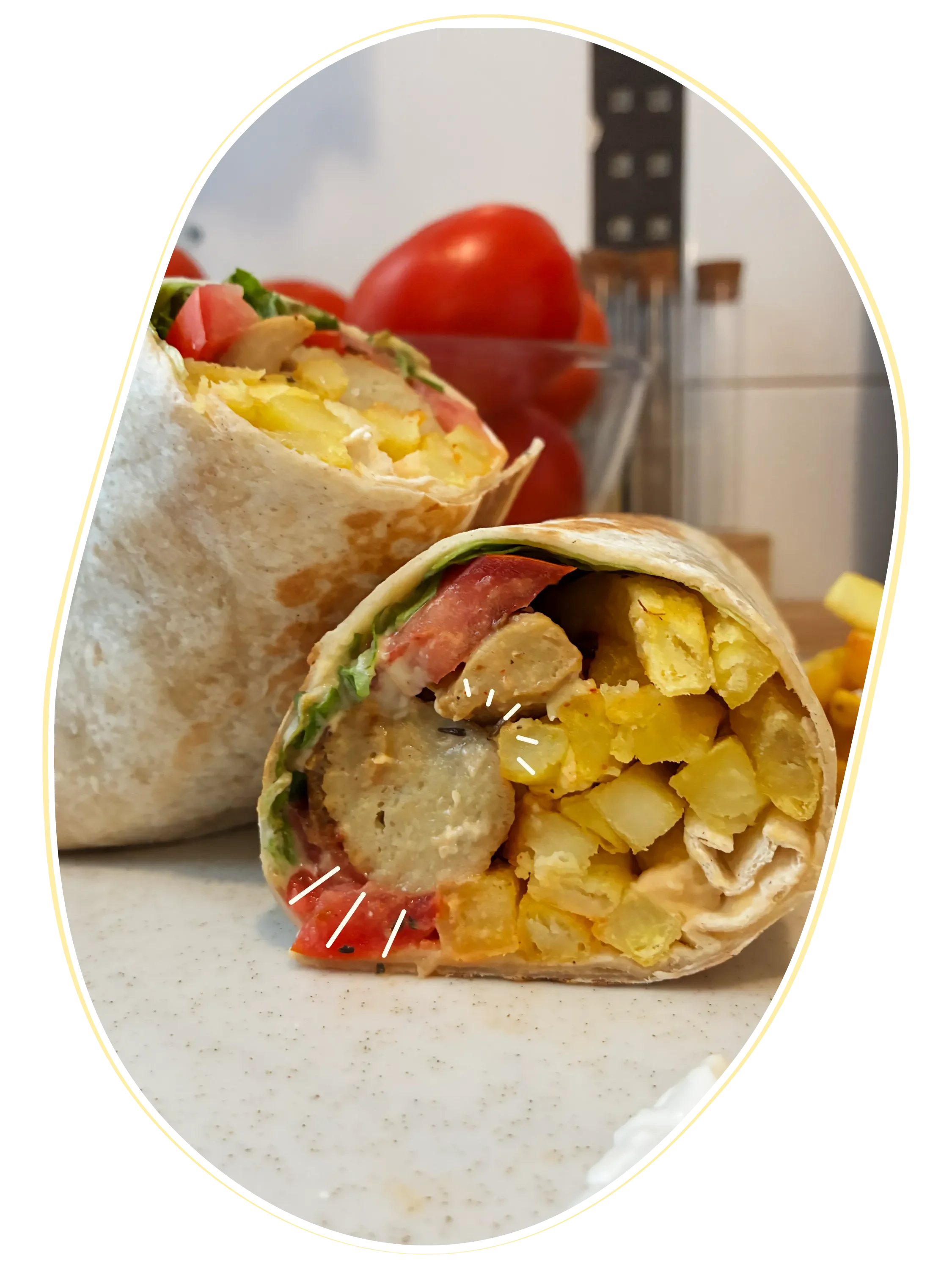 Un burrito cortado por la mitad que revela patatas fritas, tomate, lechuga y seitán en su interior, sobre un plato de cerámica blanca.
