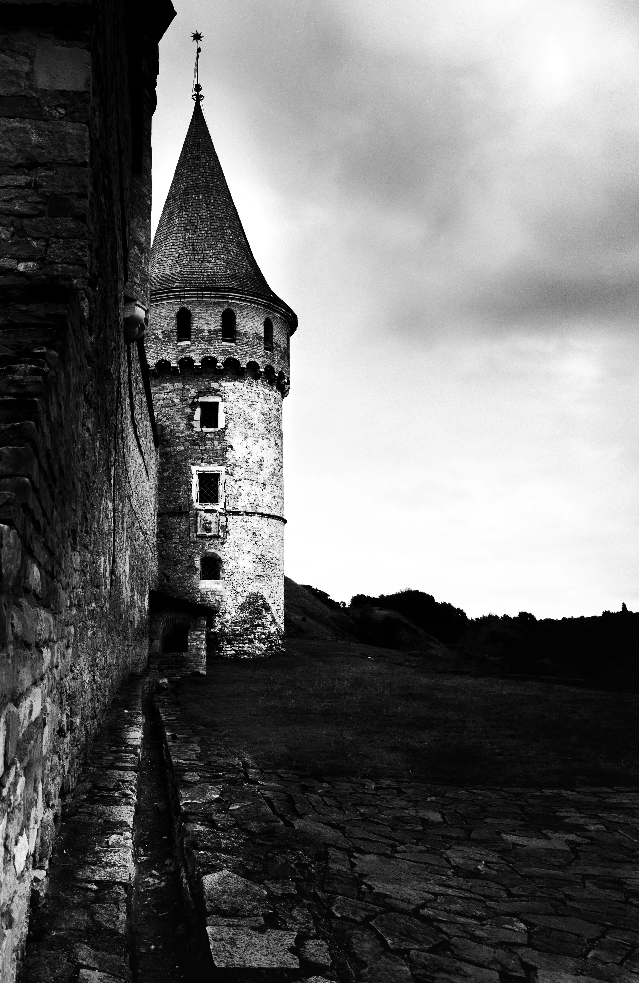 Kamianets-Podilskyi Fortress — tower of the Old Castle. The close view shifts attention from the monument as a whole to its stonework, scale and defensive character. In monochrome, the architecture feels less tied to the present and the sense of hist