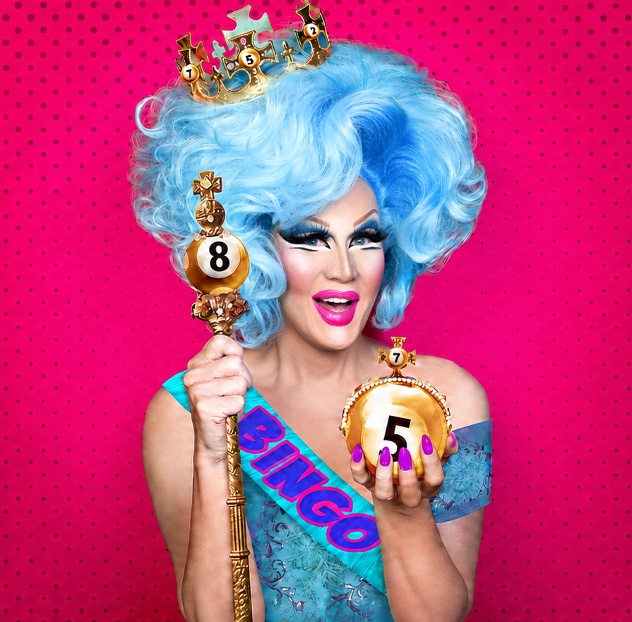 A drag queen with bright blue curly hair, bold makeup, and pink lipstick holds a gold bingo ball with the number 8 and a gold clock-shaped bingo ball with the number 5. She is wearing a blue sash that says 'BINGO' and a matching dress, standing against a pink polka-dot background.