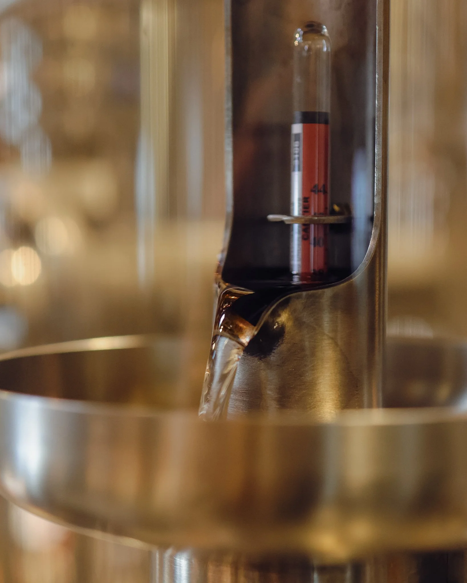 A close-up view of a metallic coffee machine with water flowing out of its spout.