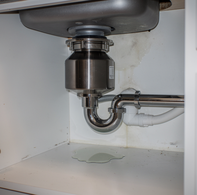 under-sink garbage disposal with exposed wiring and pipe fittings
