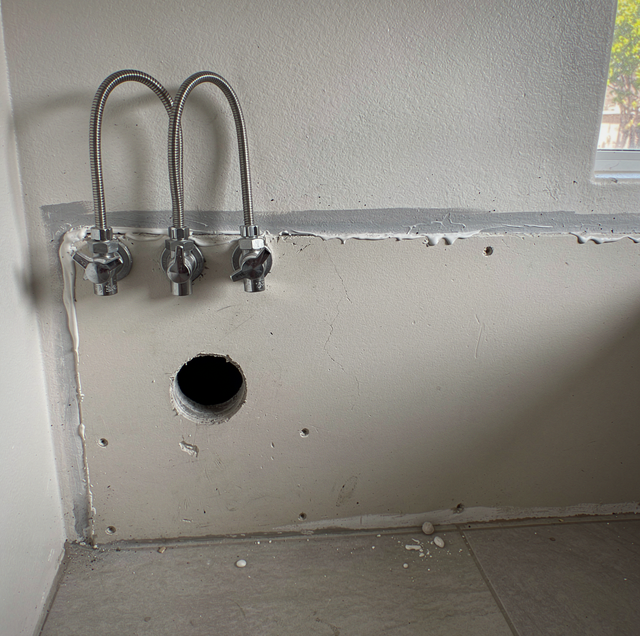 bathroom vanity with exposed shutoff valves mid-removal
