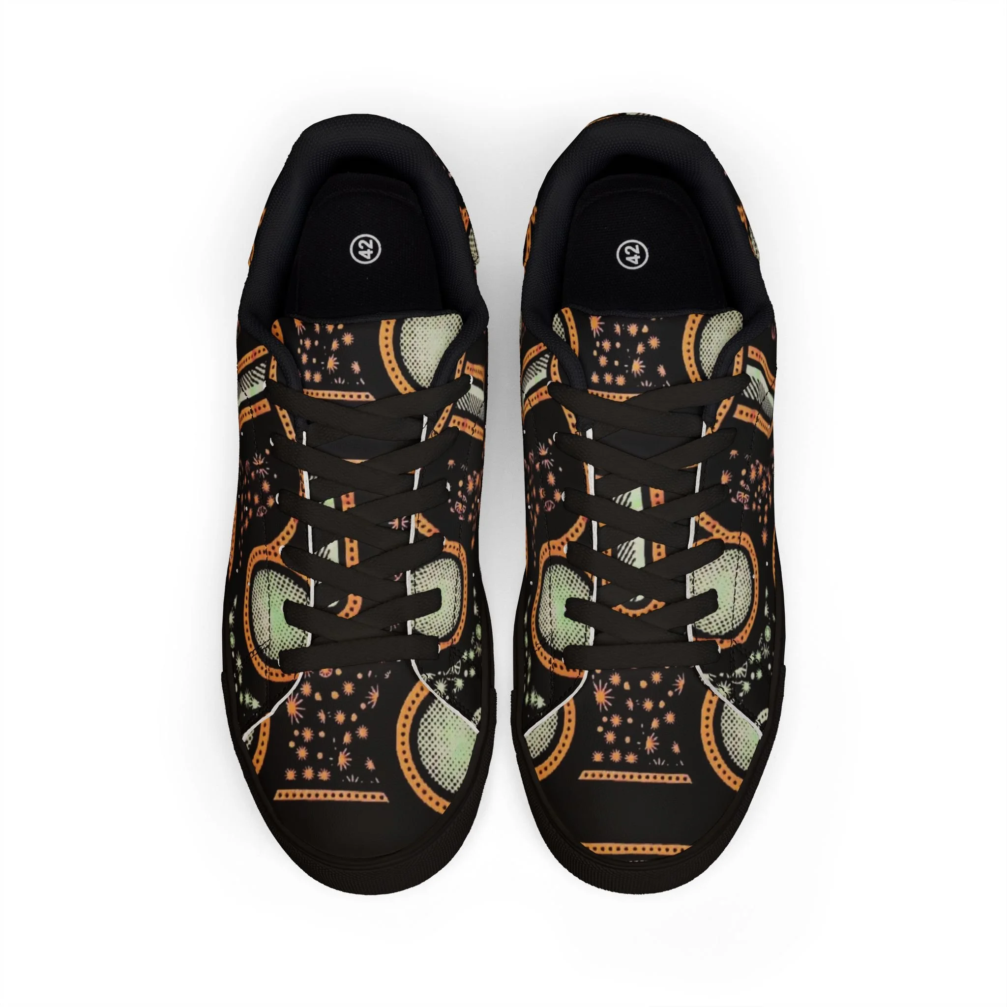 Une paire de chaussures de sport noires avec un motif coloré évoquant des motifs géométriques et floraux, vues du dessus sur un fond blanc.