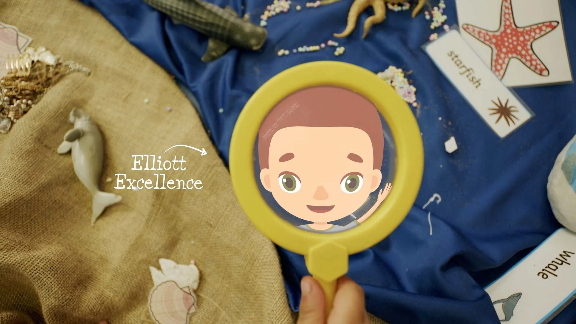 Child peers through a magnifying glass at Elliott Excellence character