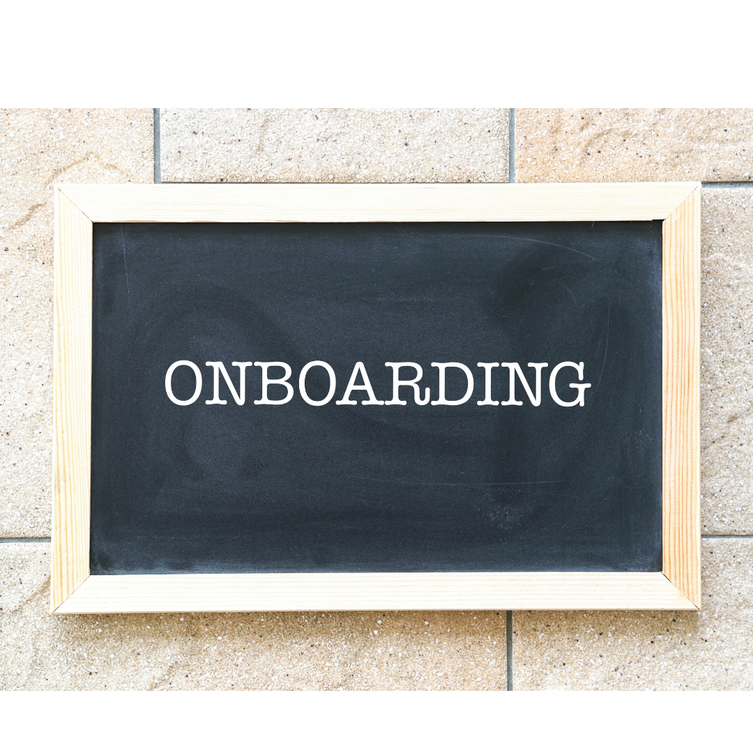 Black chalkboard with the word 'ONBOARDING' written in white, framed with light wood, on a beige tiled floor.