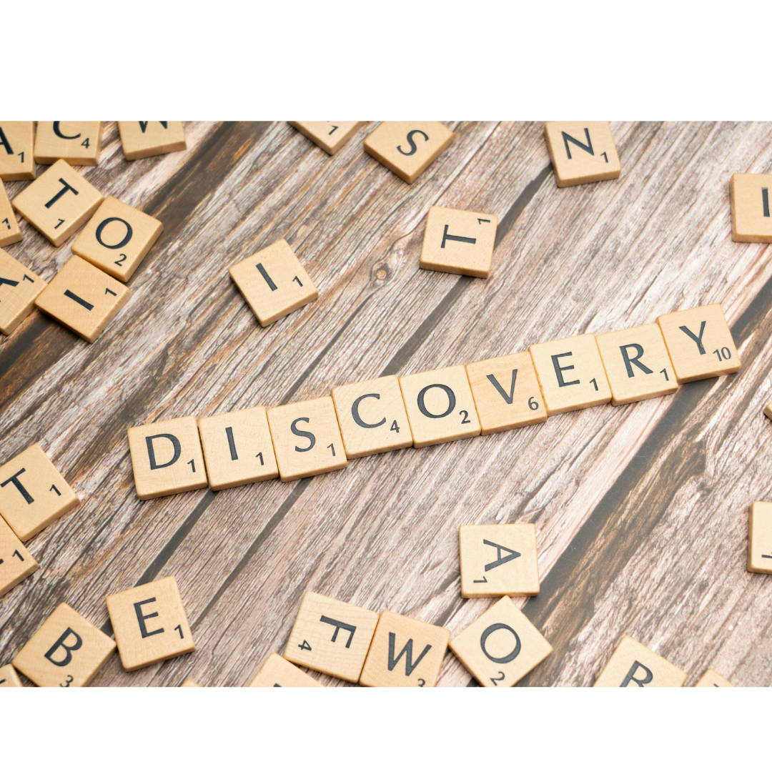 Scrabble tiles spelling 'DISCOVERY' on a wooden surface with scattered tiles around.