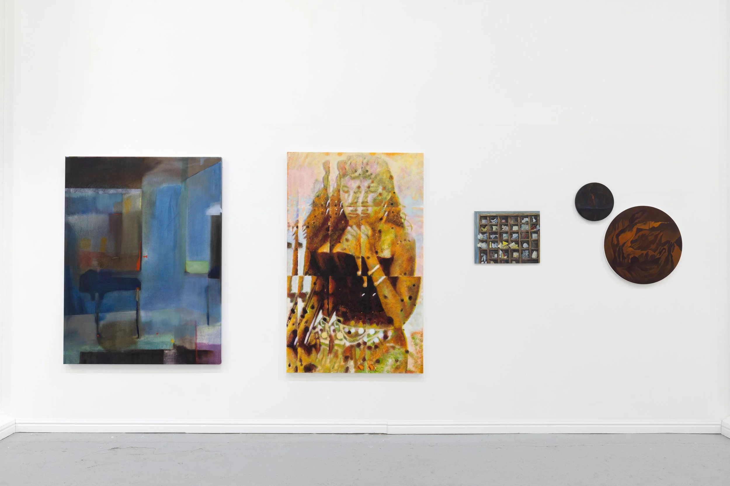 Gallery wall with abstract paintings and circular artworks in a white-walled room.
