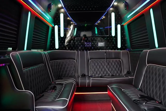 Interior of a limousine with black leather seating, LED strip lighting, and a starry ceiling.