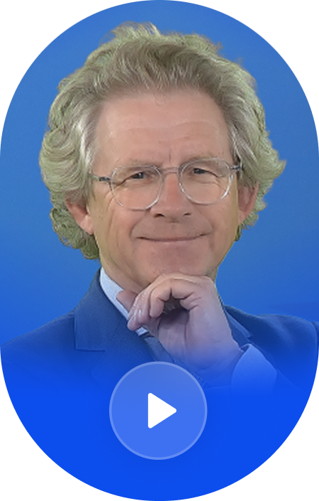 A man with curly gray hair, glasses, and a light blue shirt, smiling with one hand resting under his chin, against a blue background.