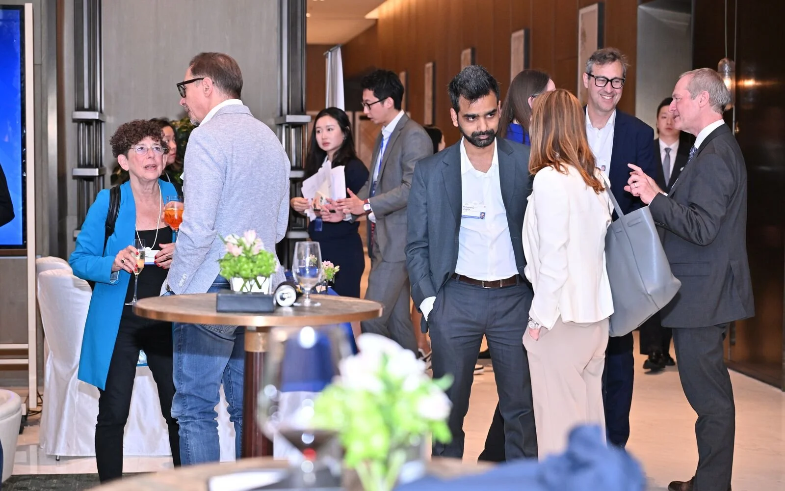 Business professionals engaging in conversations at a networking event in a modern indoor setting.