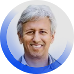 A person with gray hair smiling, wearing a blue shirt, against a blue gradient background.