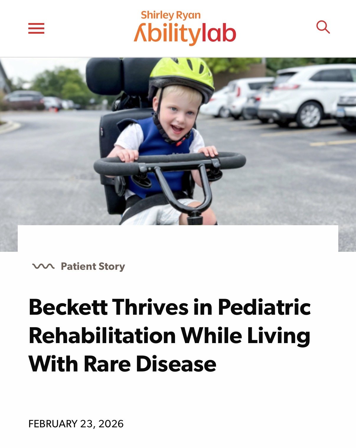 A young boy wearing a yellow helmet sitting on a tricycle in a parking lot.