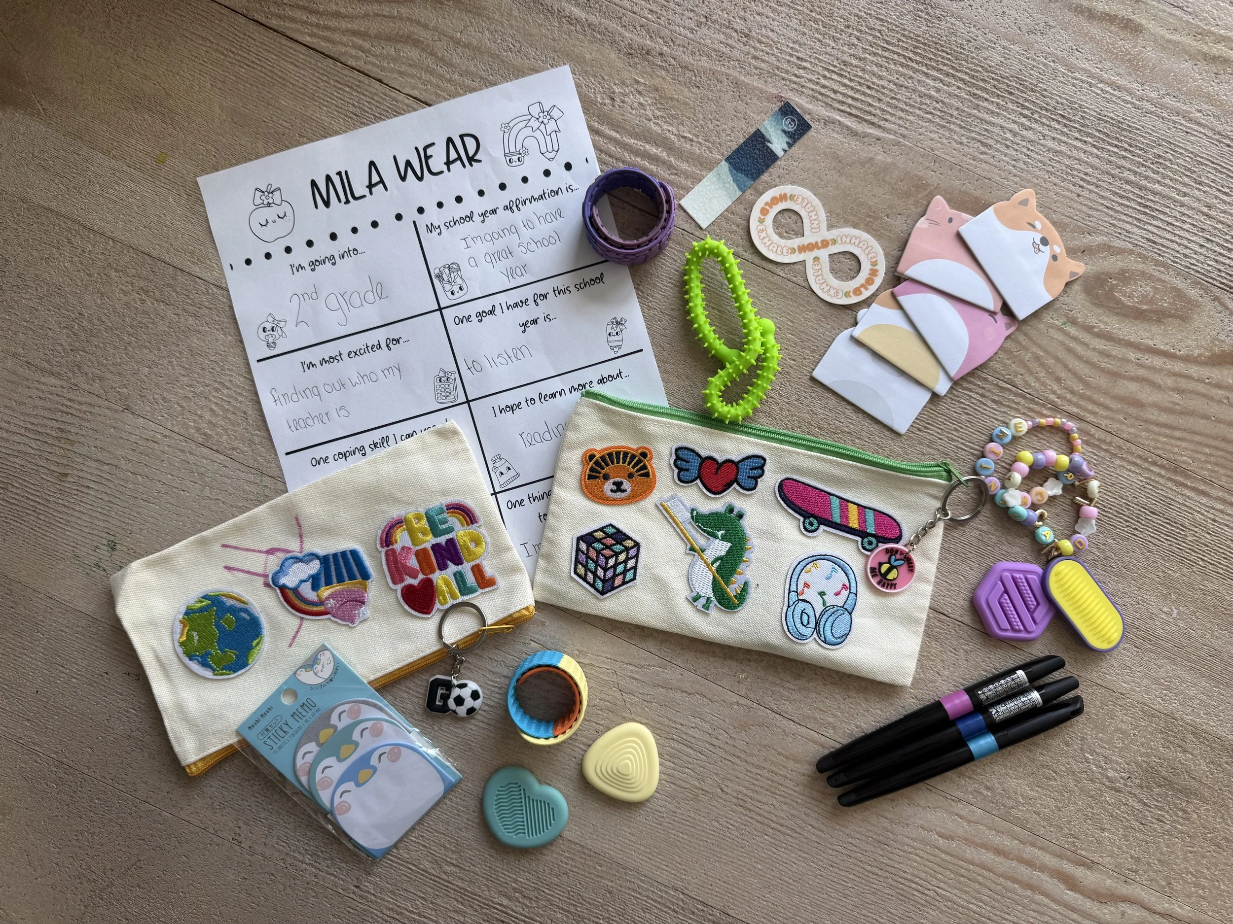 Collection of children's craft and school supplies including patches, keychains, markers, and a school affirmation worksheet.