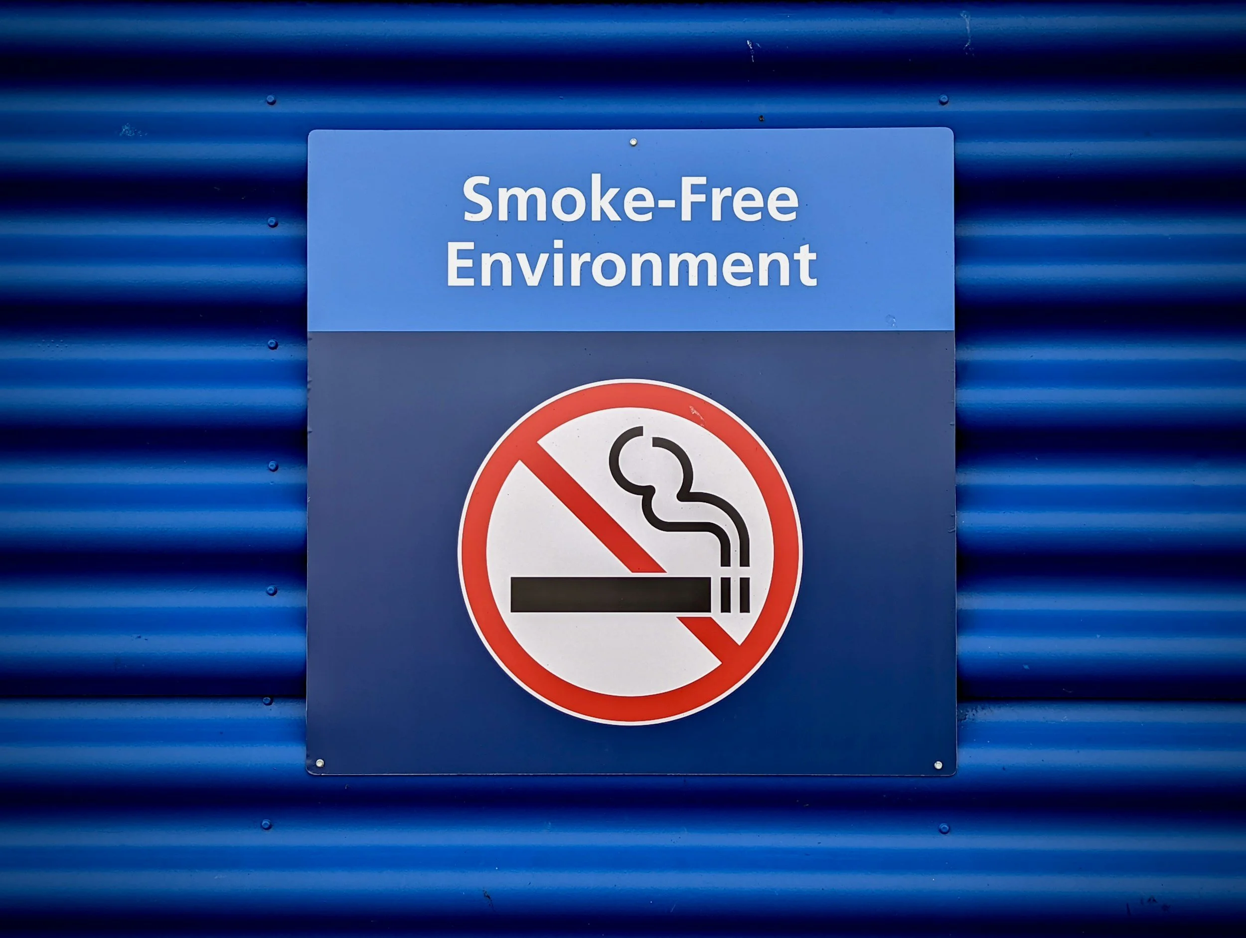 Blue wall with a sign reading "Smoke-Free Environment" and a no smoking symbol.