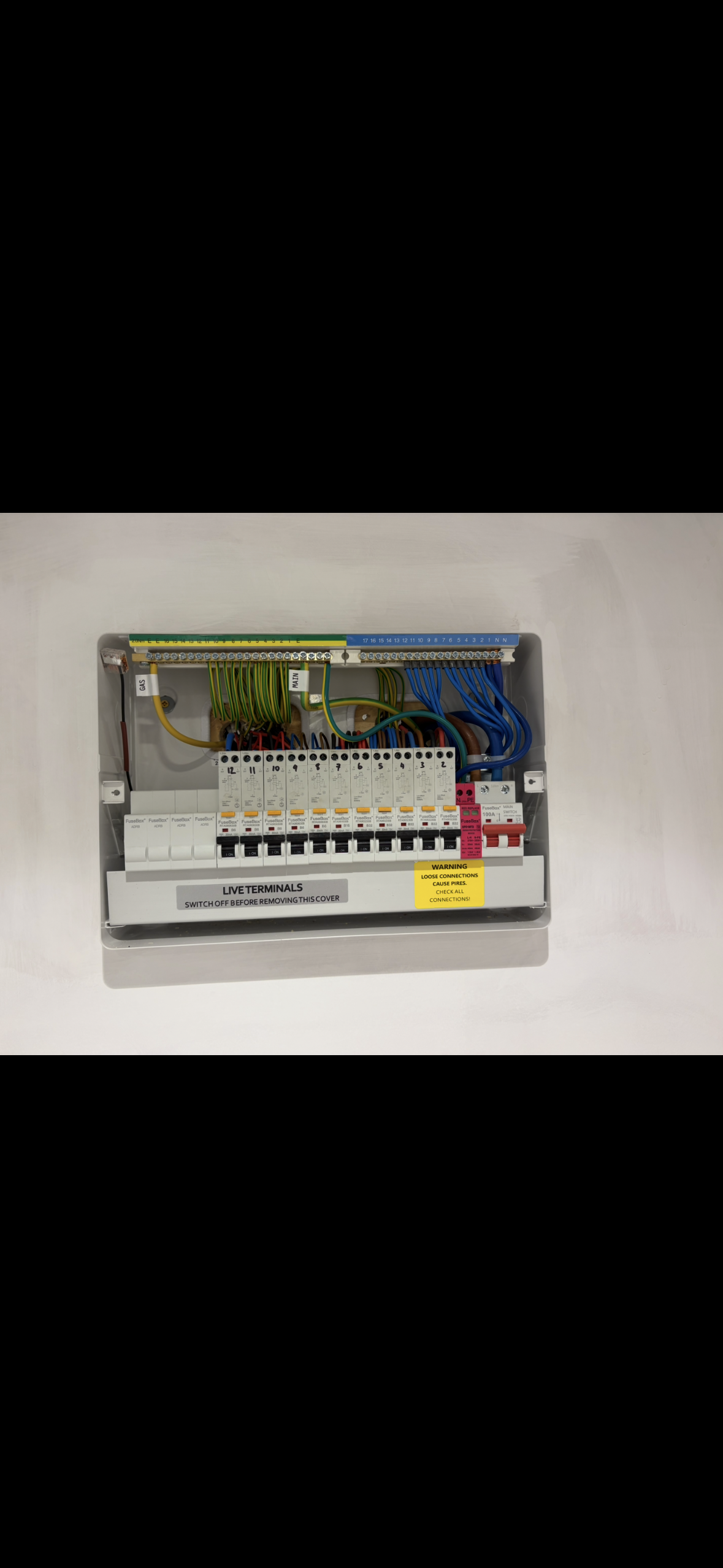 Open electrical breaker panel with multiple circuit breakers and various colored wires inside.