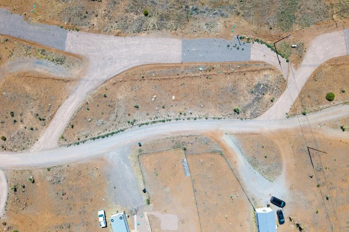 Aerial view of a remote area with unpaved roads, some small buildings, and sparse vegetation.