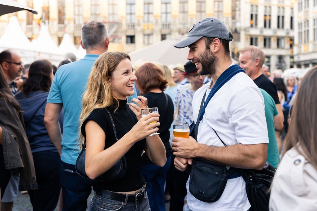 Twee mensen die lachen en drinken tijdens Belgian Beer Weekend op de Grote Markt van Brussel.