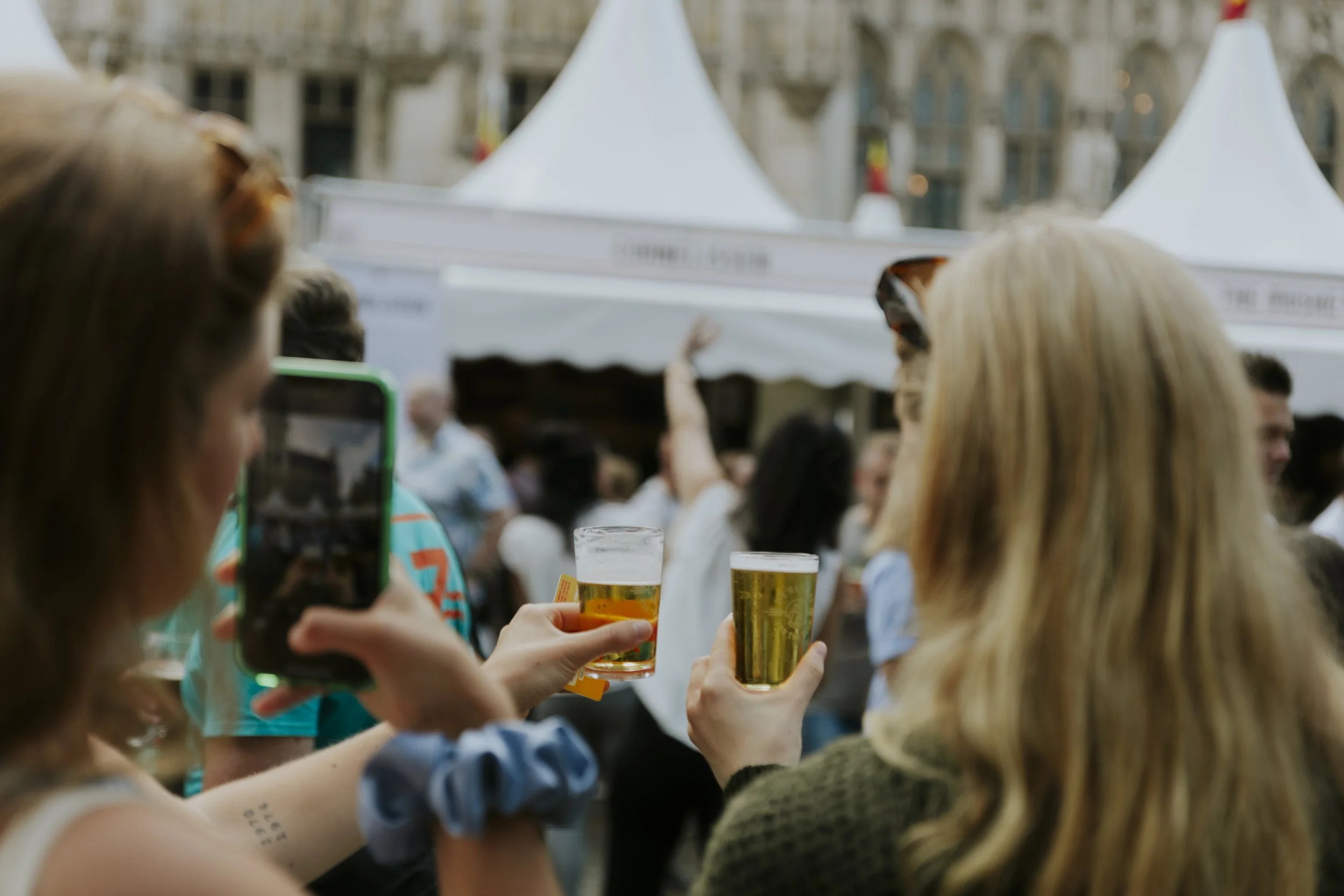 Overzicht van een zonnig terras op het Beursplein vol bezoekers die genieten van Belgisch speciaalbier tijdens Belgian Beer Weekend.