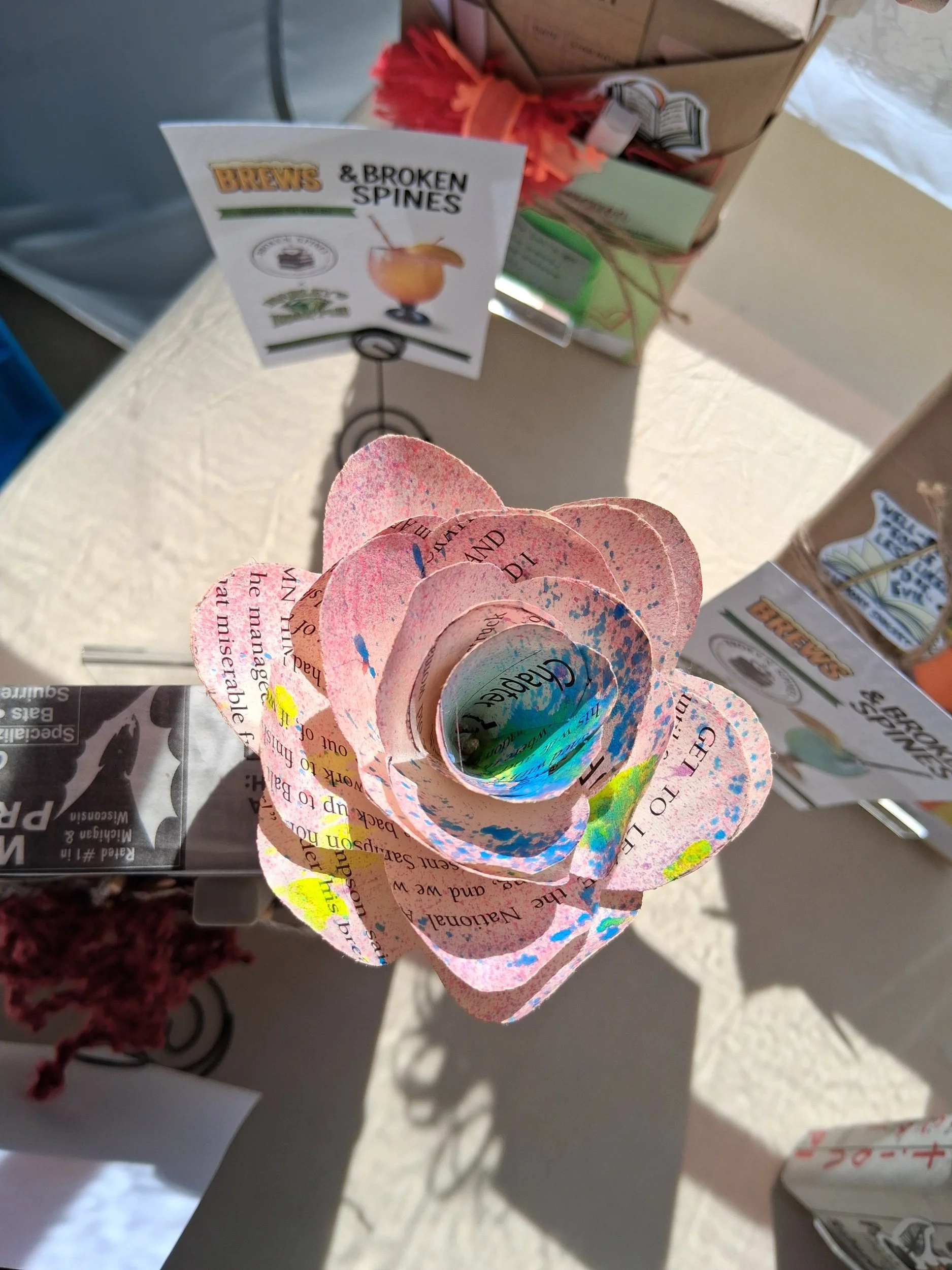 Colorful paper hearts with printed text, hanging from a wire stand.
