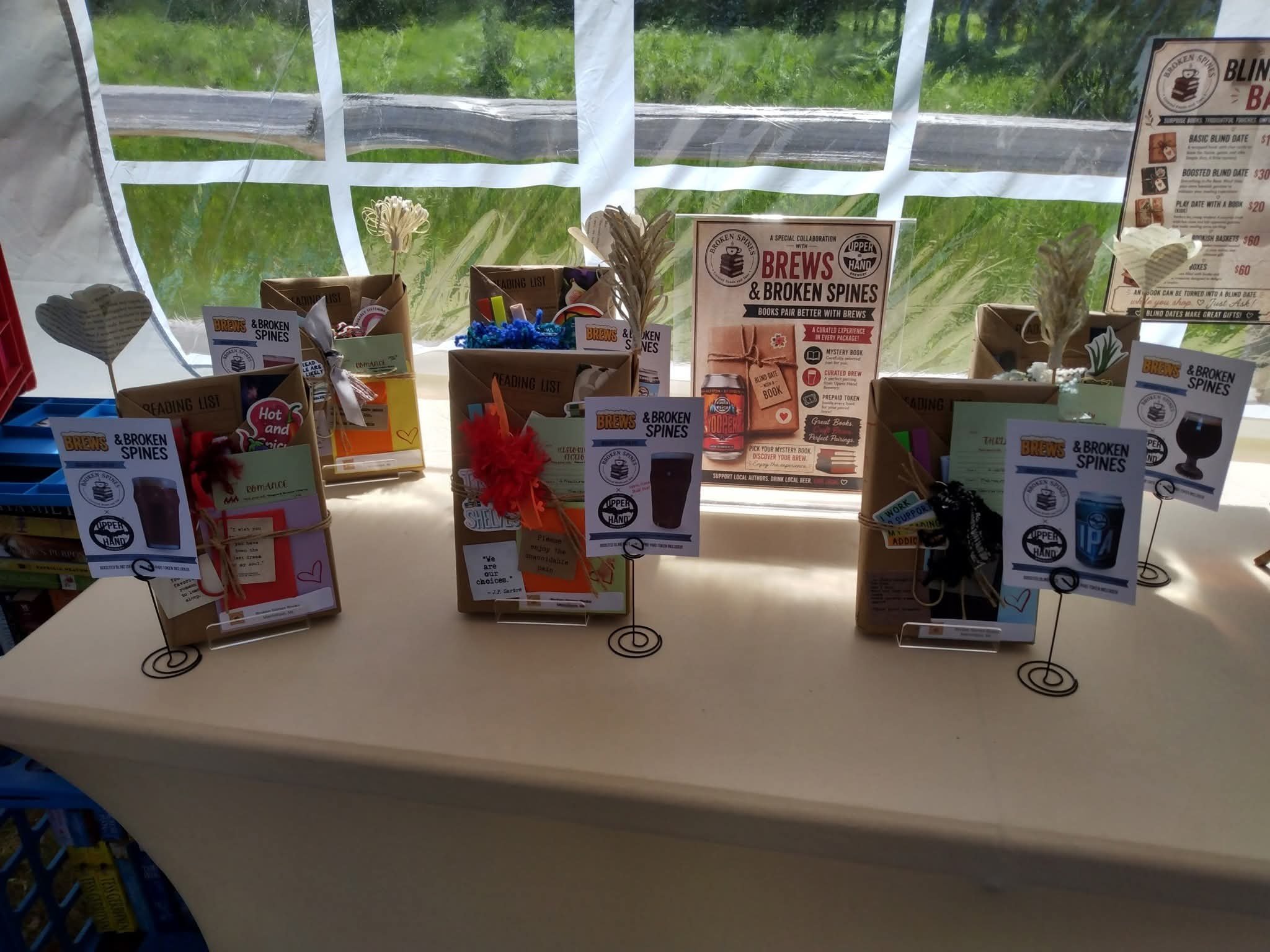 Display of books about brewing and broken spines on a table, with informational signs and decorative items in front of a window showing greenery outside.
