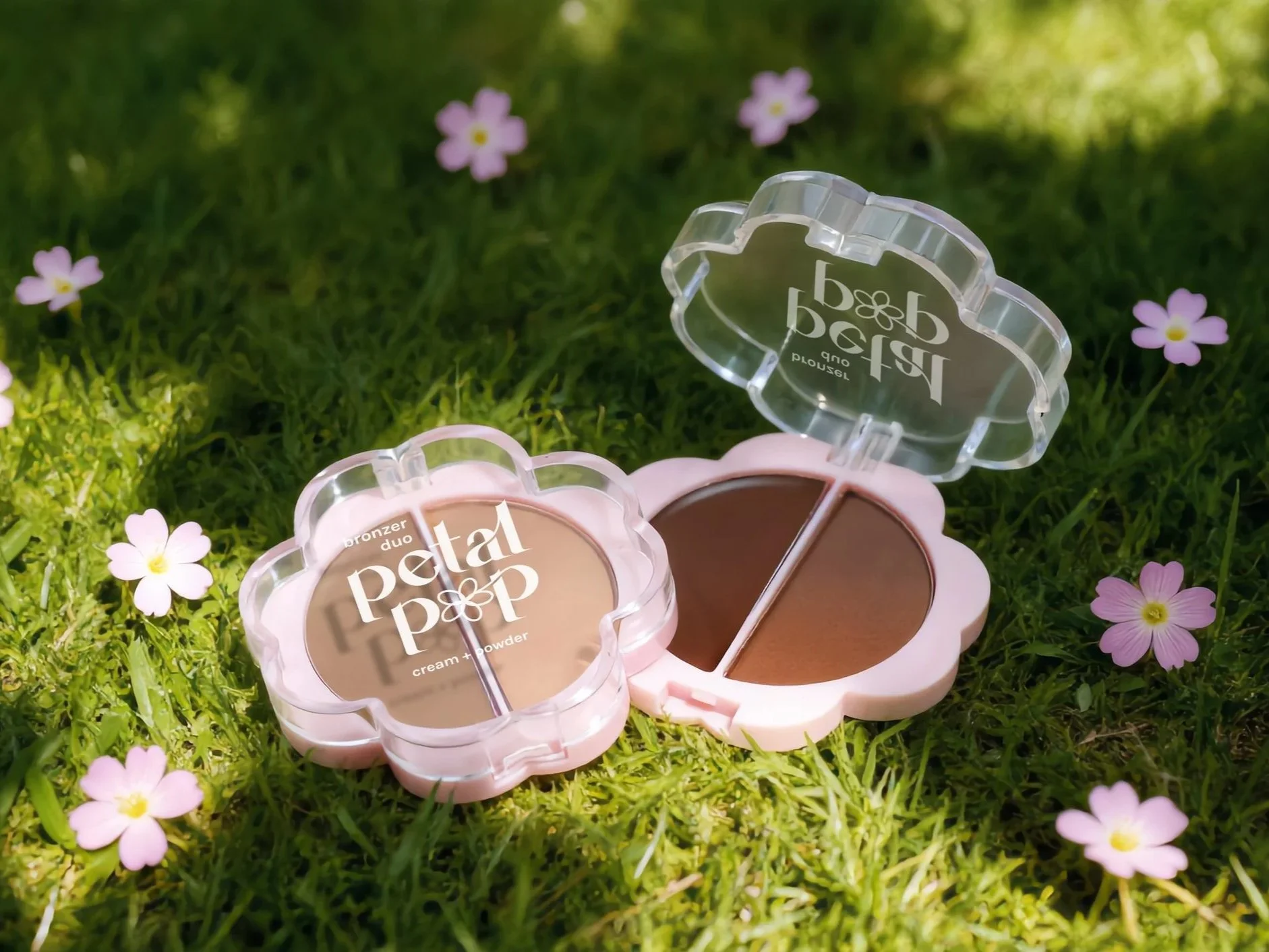 Image of the AOA Studio Petal Pop Bronzer duo on a grassy field with pink flowers.