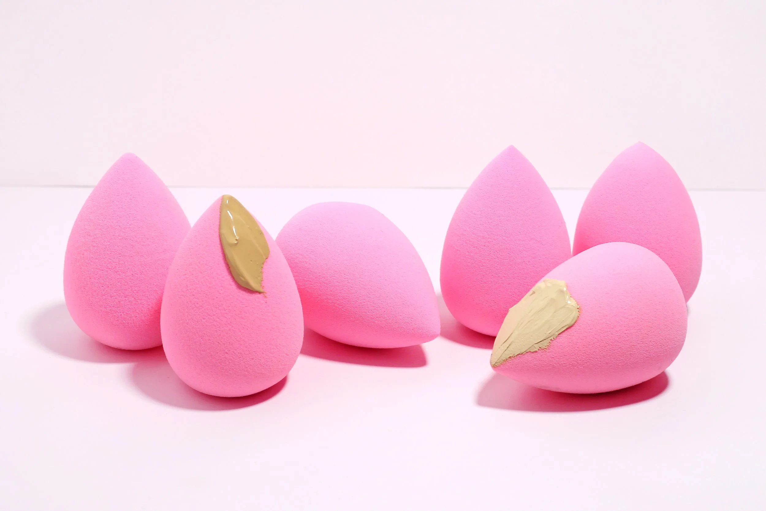 A styled image of a few Paw Paw Super Soft Wonder Blenders and some makeup smears