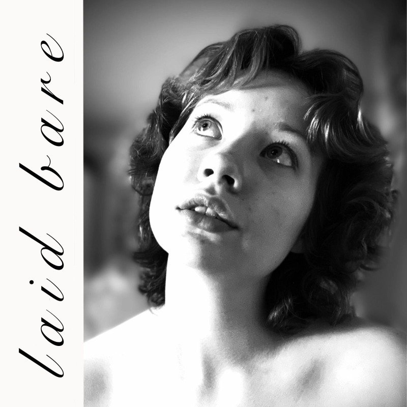Black and white album cover of a young woman (Amie Wren) with curly hair looking upward, with the words "laid bare" written vertically on the left side.