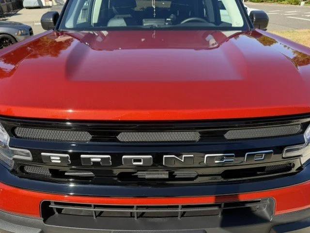 Front view of a red Ford Bronco SUV with black grille and large Bronco badge.