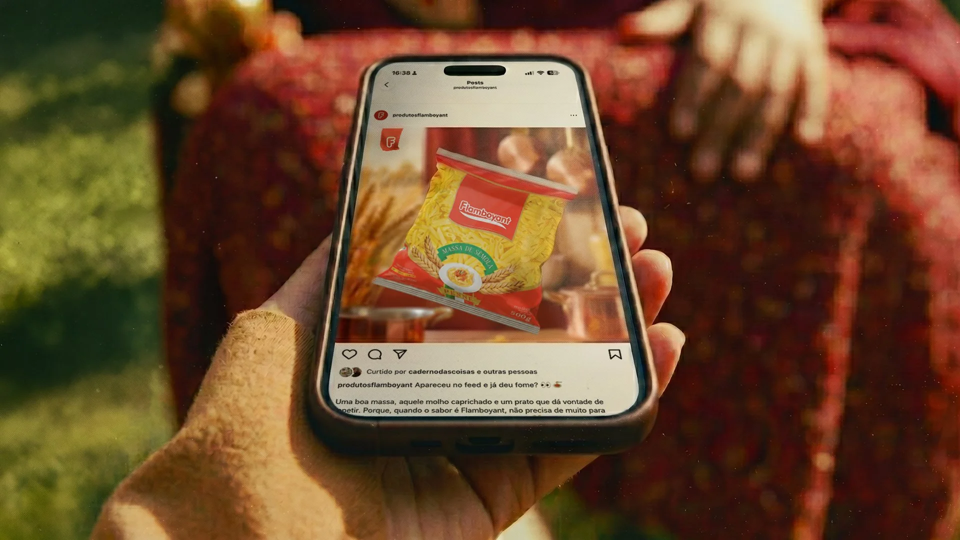 Pontuação de uma embalagem de massa de sêmola de trigo brand Famboyant, amplamente exibida em uma tela de celular, com fundo desfocado de uma área externa com gramado e estrutura de madeira.