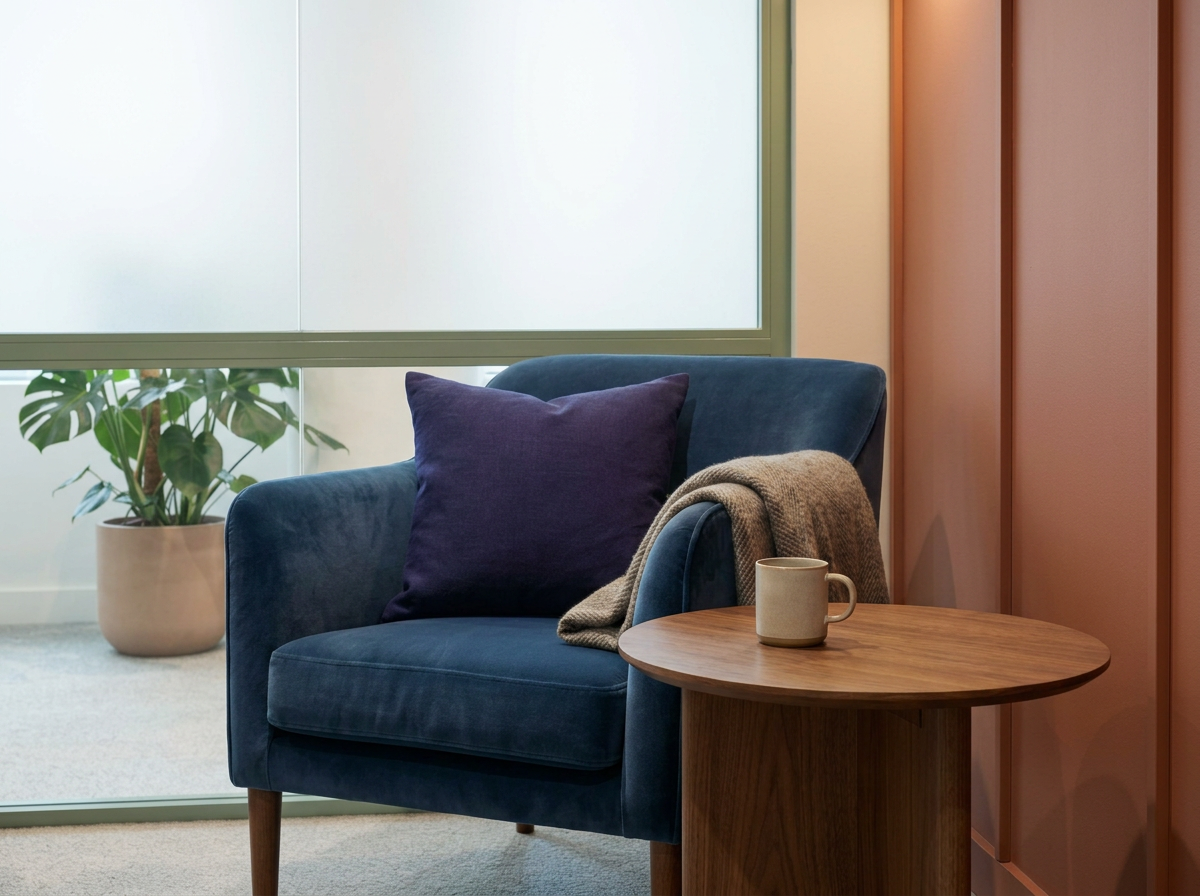Therapy Room N1, A blue velvet arm chair with blue cushion and brown blanket next to a brown wooden coffee table with a cream mug on it