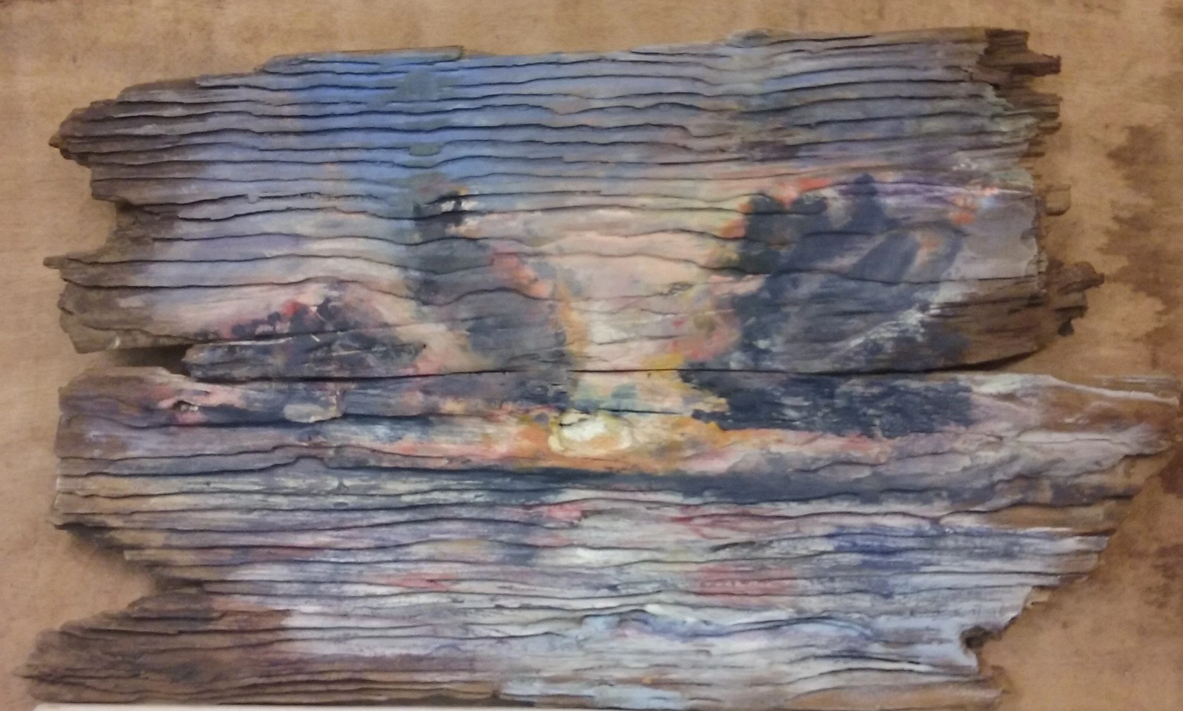 Stacks of colorful, weathered, wooden slats arranged in rows on a wooden surface.
